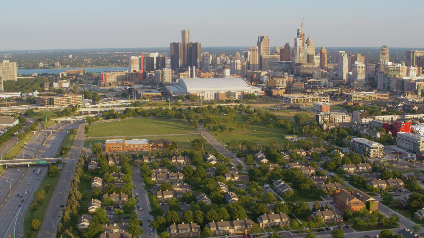 A vibrant aerial view of Detroit, Michigan, showcasing its iconic skyline, urban green spaces, and residential areas.