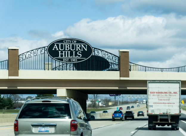 Traffic passing the sign at the border of Auburn Hills, Michigan along the I-75 Interstate.